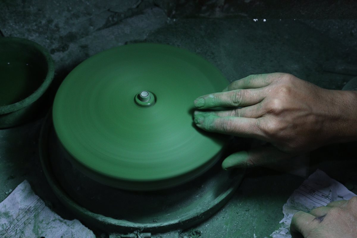 Shaping a gemstone on a grinding wheel in the DWS Jewellery gemstone department